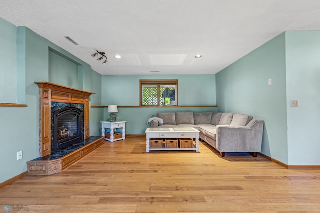 living room with a textured ceiling, a fireplace, rail lighting, and hardwood / wood-style floors