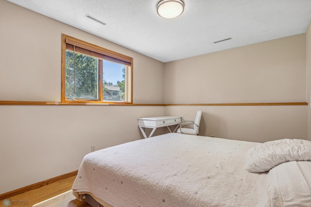 bedroom with hardwood / wood-style floors and a textured ceiling