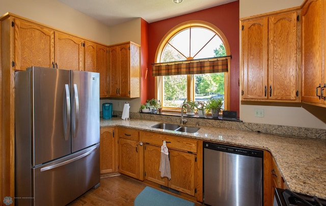 kitchen featuring sink, dishwashing machine, dark wood-type flooring, light stone counters, and fridge