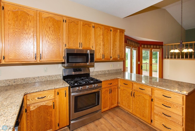 kitchen with light wood-type flooring, vaulted ceiling, stainless steel appliances, and light stone countertops