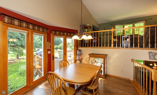 dining space with hardwood / wood-style flooring, a notable chandelier, and lofted ceiling