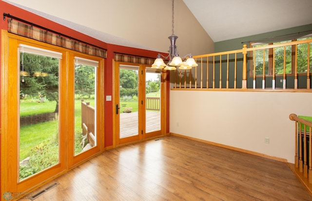 unfurnished dining area with high vaulted ceiling, hardwood / wood-style floors, and a chandelier