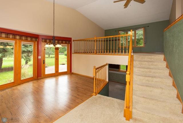 interior space with high vaulted ceiling, ceiling fan with notable chandelier, and wood-type flooring