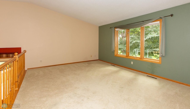 carpeted empty room with vaulted ceiling