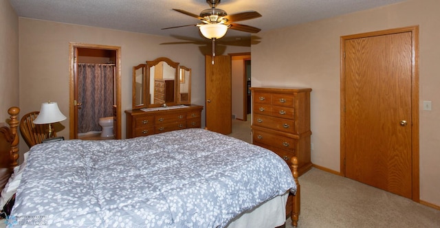 carpeted bedroom featuring a textured ceiling, a closet, ceiling fan, and ensuite bath