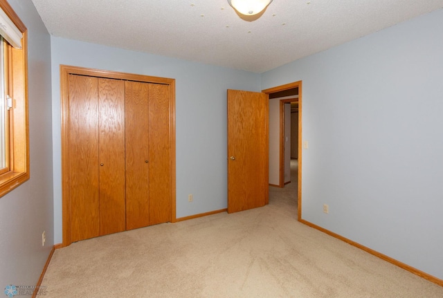 unfurnished bedroom featuring a closet, light carpet, and a textured ceiling