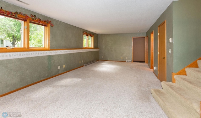 carpeted empty room with a baseboard heating unit