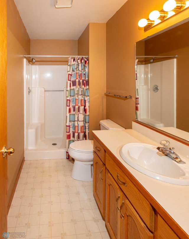 bathroom featuring tile patterned flooring, curtained shower, vanity, and toilet