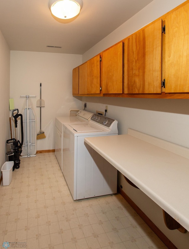 clothes washing area featuring washer and clothes dryer, cabinets, and light tile patterned floors