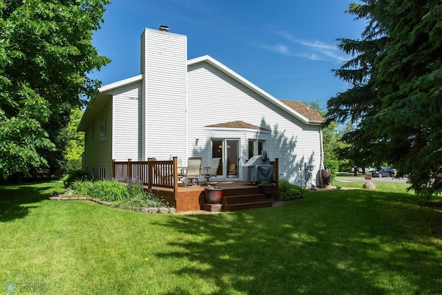 rear view of house featuring a wooden deck and a lawn