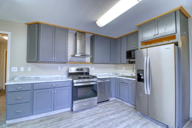 kitchen with wall chimney exhaust hood, light wood-type flooring, gray cabinets, appliances with stainless steel finishes, and sink