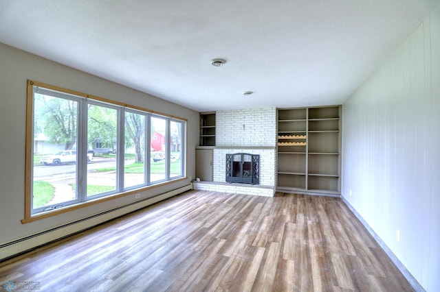 unfurnished living room featuring a fireplace, hardwood / wood-style flooring, baseboard heating, and brick wall