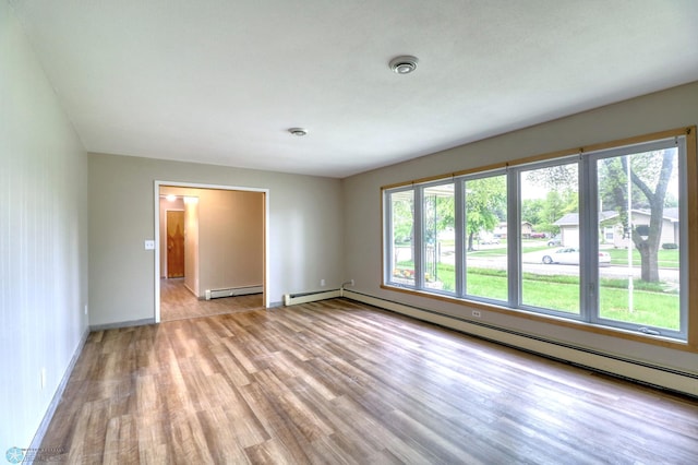 unfurnished room featuring a baseboard radiator and light hardwood / wood-style floors