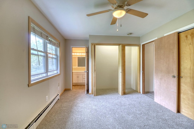 unfurnished bedroom with a baseboard radiator, ceiling fan, two closets, ensuite bath, and carpet floors