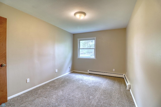 carpeted spare room with a baseboard heating unit