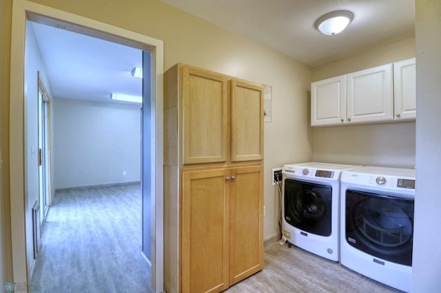 laundry area featuring washer and dryer, cabinets, and light hardwood / wood-style floors