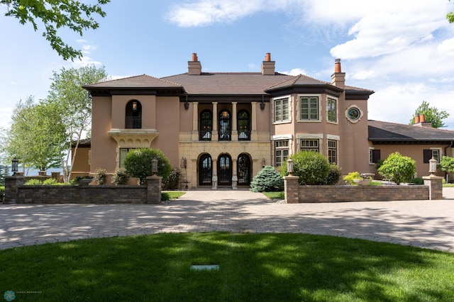 view of front of house with a front yard, french doors, and a balcony