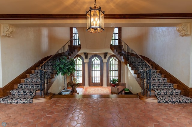 tiled entryway with a chandelier, ornamental molding, and plenty of natural light