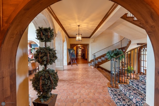 entryway featuring a chandelier, crown molding, and tile floors