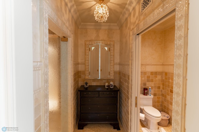 bathroom featuring a notable chandelier, vanity, toilet, and tile walls