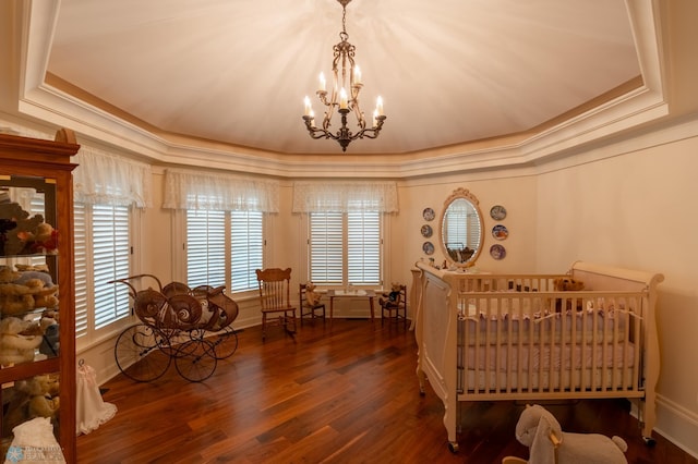 bedroom featuring a chandelier, hardwood / wood-style flooring, a raised ceiling, and ornamental molding