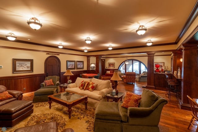 living room with ornate columns, hardwood / wood-style floors, and crown molding