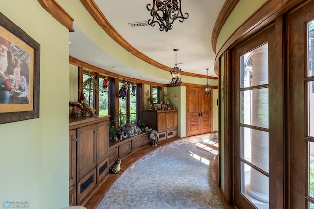 interior space featuring a healthy amount of sunlight, an inviting chandelier, hardwood / wood-style floors, and crown molding