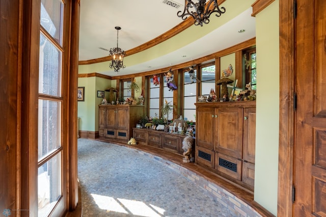 living room featuring a notable chandelier, hardwood / wood-style flooring, a healthy amount of sunlight, and crown molding