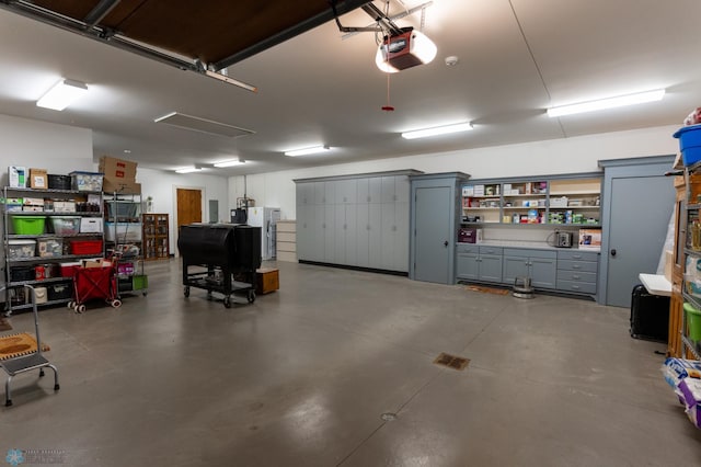 garage with a garage door opener and stainless steel fridge