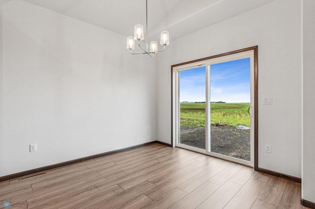 unfurnished room featuring a chandelier and light wood-type flooring