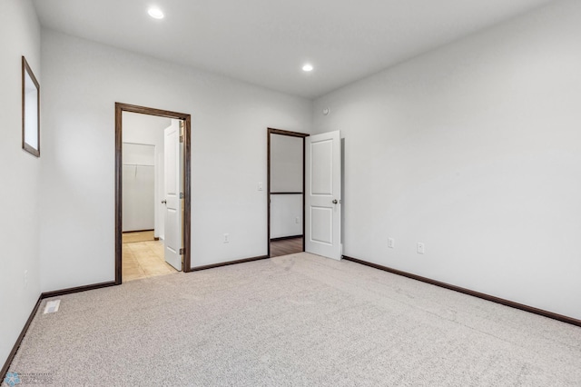 unfurnished bedroom with light carpet, a walk in closet, and a closet