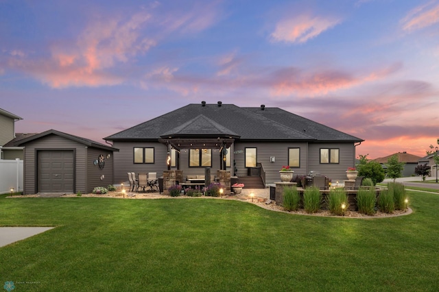 back house at dusk with a garage and a lawn