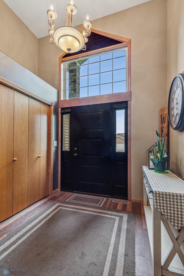 foyer entrance with a notable chandelier, plenty of natural light, and dark hardwood / wood-style flooring