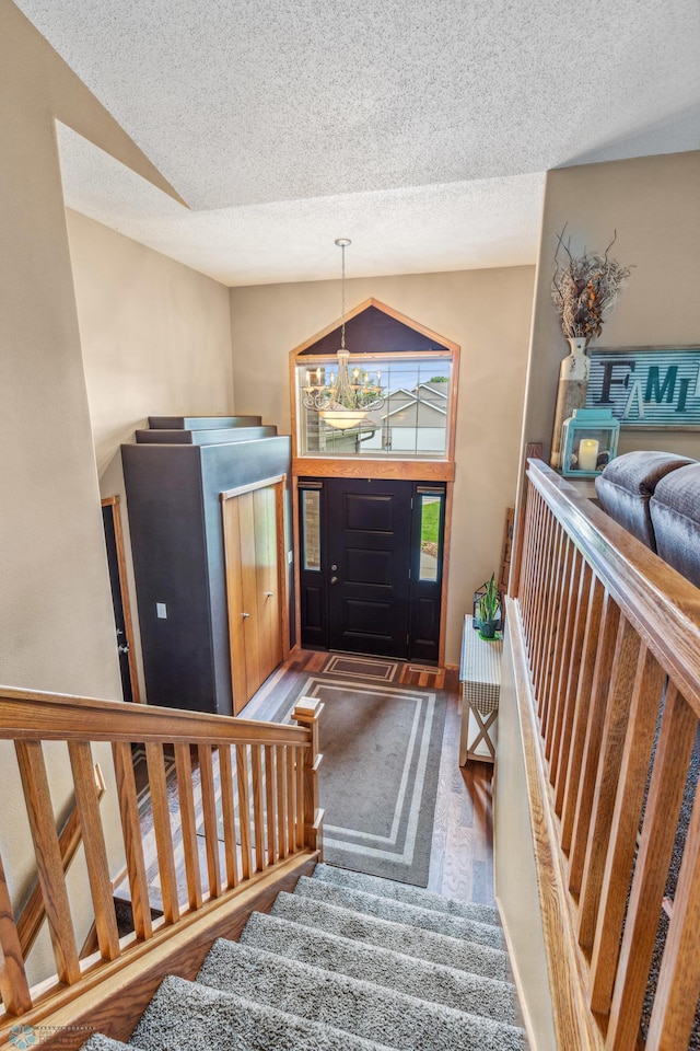 entryway featuring carpet floors, a textured ceiling, lofted ceiling, and a chandelier