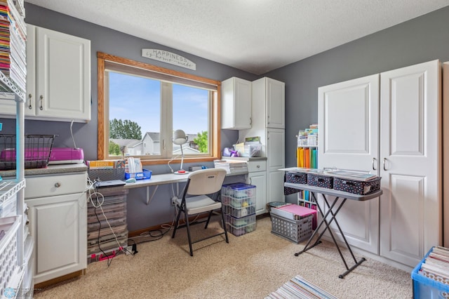 carpeted home office with built in desk and a textured ceiling