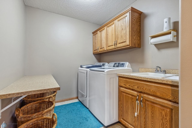 washroom featuring washing machine and dryer, a textured ceiling, light tile floors, sink, and cabinets