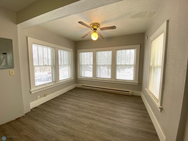 unfurnished dining area with a baseboard heating unit, a textured ceiling, dark wood-type flooring, and ceiling fan