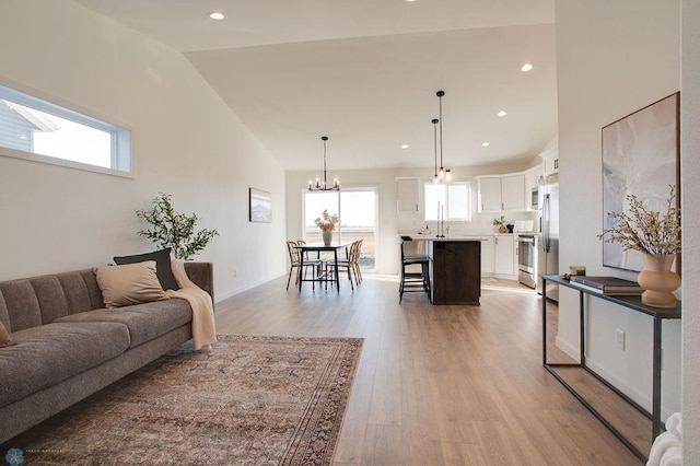 living room featuring high vaulted ceiling, hardwood / wood-style flooring, and an inviting chandelier