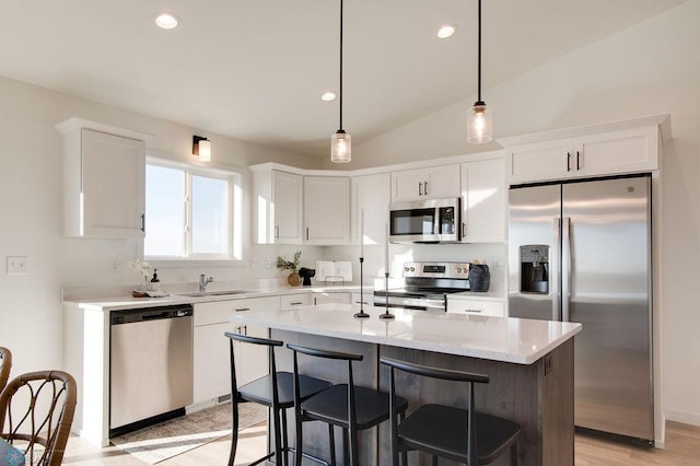 kitchen featuring vaulted ceiling, light hardwood / wood-style flooring, hanging light fixtures, a center island, and appliances with stainless steel finishes