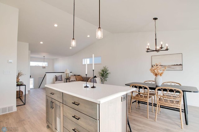 kitchen featuring light hardwood / wood-style floors, pendant lighting, a notable chandelier, a center island, and lofted ceiling