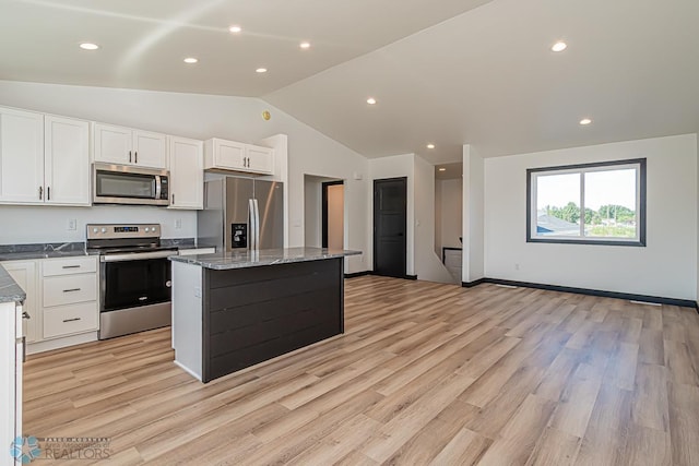 kitchen featuring light stone counters, light hardwood / wood-style floors, lofted ceiling, white cabinets, and appliances with stainless steel finishes