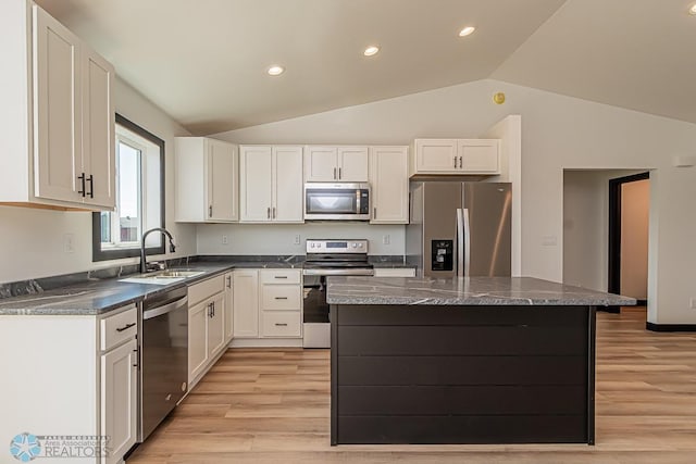 kitchen with stainless steel appliances, vaulted ceiling, sink, and a center island