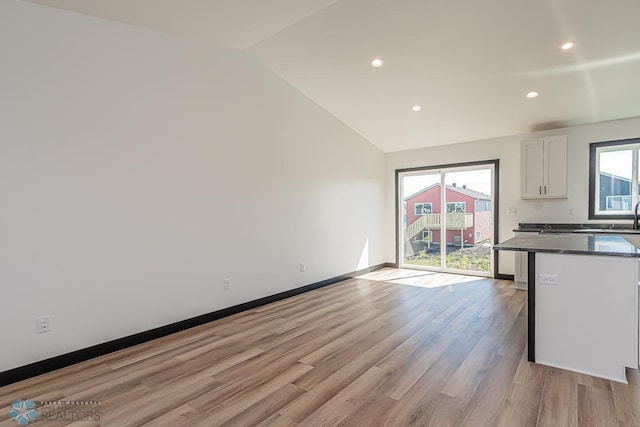 unfurnished living room with a healthy amount of sunlight, light hardwood / wood-style flooring, and lofted ceiling