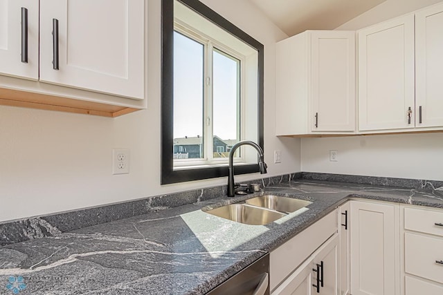 kitchen featuring white cabinets, sink, and dark stone counters