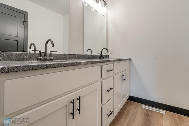 bathroom with dual bowl vanity and hardwood / wood-style floors