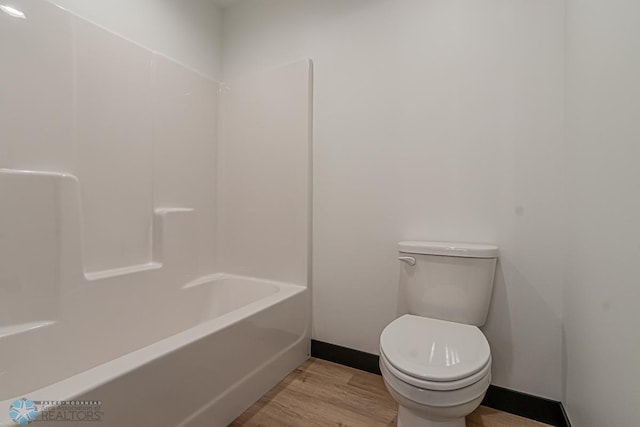 bathroom featuring wood-type flooring, toilet, and shower / bathing tub combination