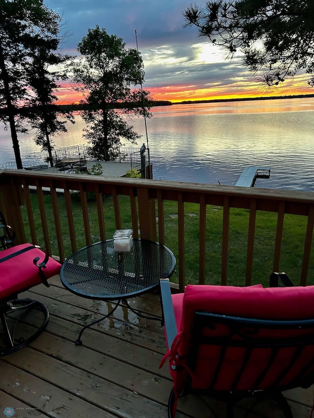 deck at dusk with a water view and a yard