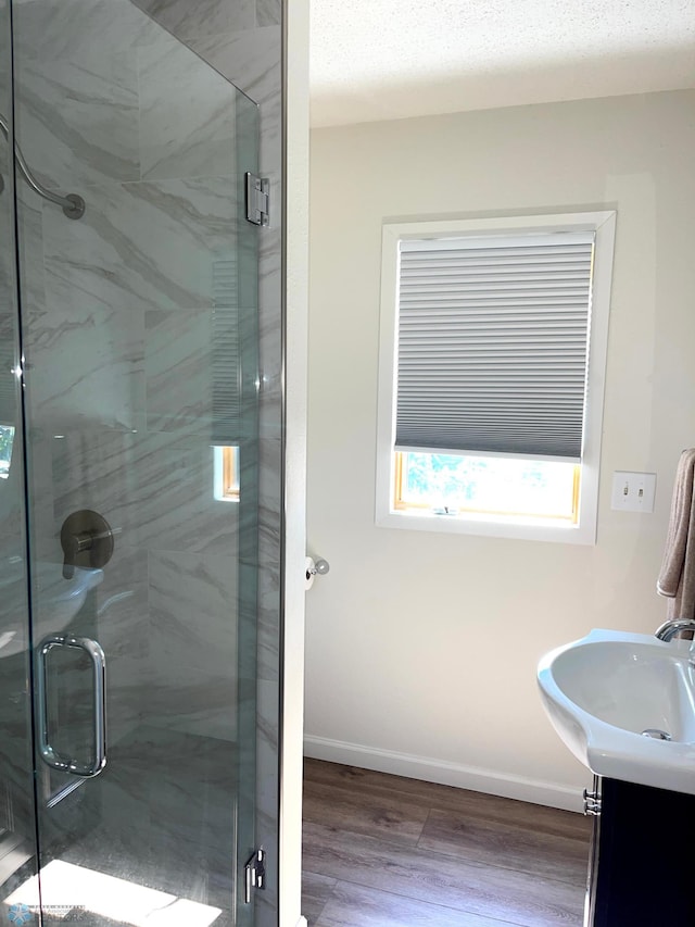 bathroom featuring vanity, a textured ceiling, hardwood / wood-style floors, and a shower with door