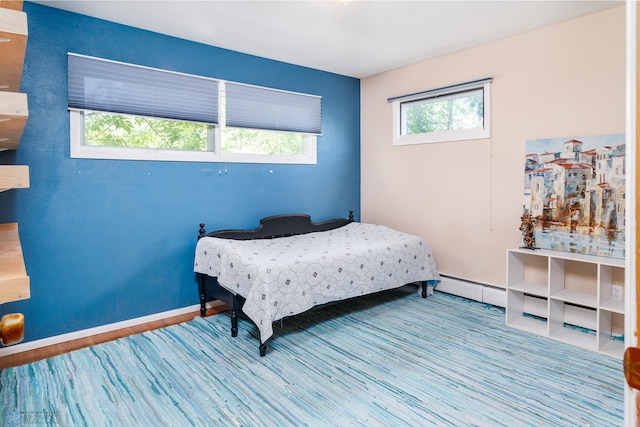 bedroom featuring a baseboard heating unit and hardwood / wood-style flooring