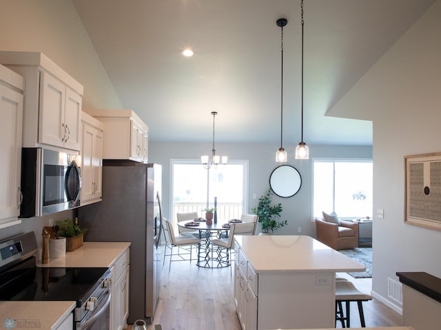 kitchen featuring appliances with stainless steel finishes, decorative light fixtures, light hardwood / wood-style floors, and white cabinets